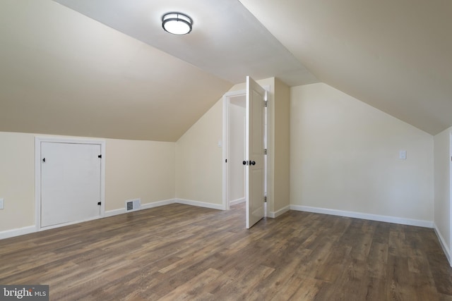 additional living space with visible vents, baseboards, vaulted ceiling, and wood finished floors