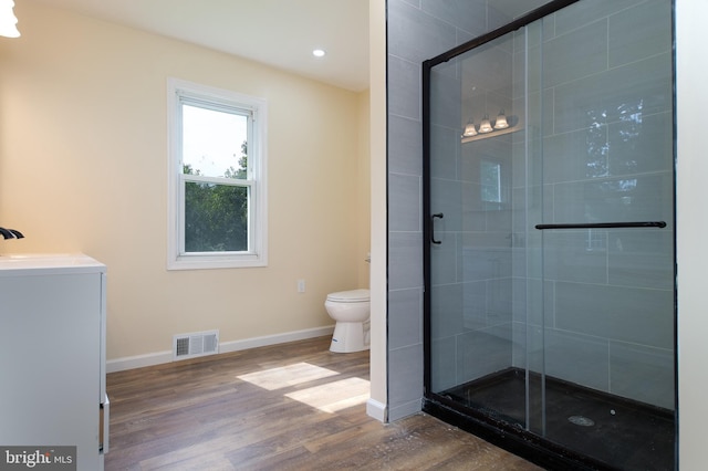 full bathroom featuring baseboards, a stall shower, toilet, visible vents, and wood finished floors