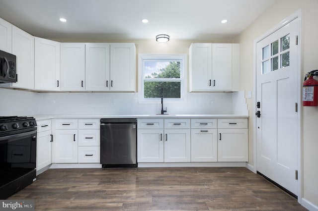 kitchen featuring white cabinetry, black appliances, dark wood-style flooring, a sink, and decorative backsplash