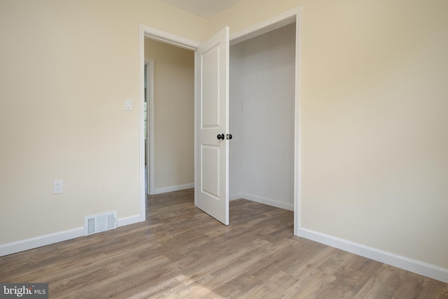 empty room featuring visible vents, light wood-style flooring, and baseboards