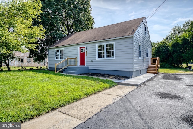 view of front facade featuring a front yard and a shingled roof