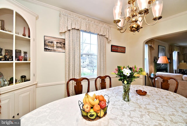 dining space featuring an inviting chandelier, arched walkways, a healthy amount of sunlight, and ornamental molding