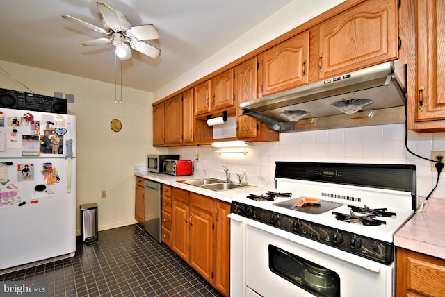 kitchen featuring light countertops, under cabinet range hood, a sink, appliances with stainless steel finishes, and backsplash