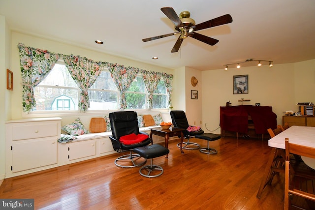 living area with a ceiling fan, track lighting, wood finished floors, and plenty of natural light