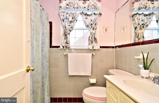 full bathroom with vanity, tile walls, a wealth of natural light, and a wainscoted wall