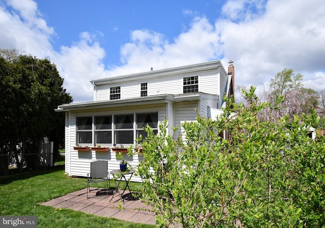 rear view of property with a lawn, fence, and a chimney