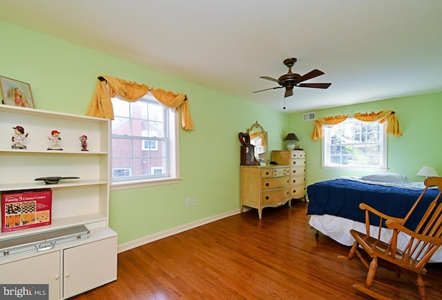 bedroom with baseboards, ceiling fan, wood finished floors, and visible vents
