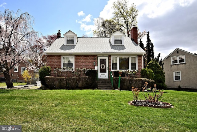 cape cod home with a chimney, a front yard, and brick siding