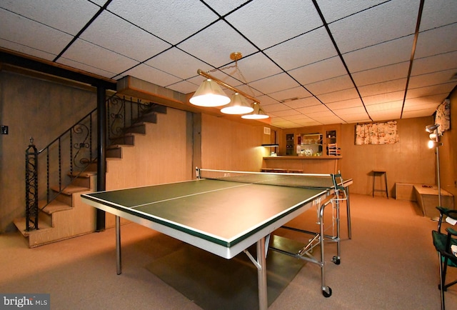playroom featuring carpet floors, indoor bar, a drop ceiling, and wooden walls