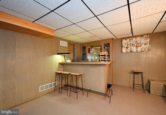 bar featuring wooden walls, visible vents, a dry bar, and a drop ceiling