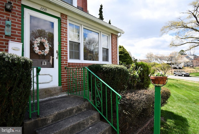 doorway to property featuring brick siding and a yard