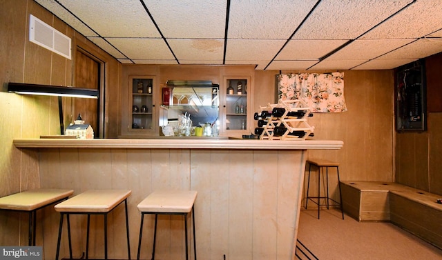 bar featuring carpet flooring, wooden walls, visible vents, and a paneled ceiling