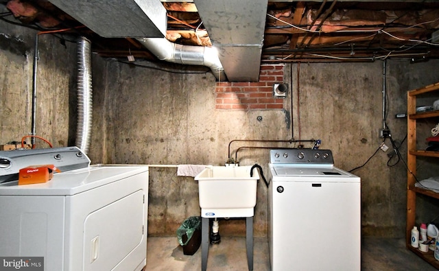 washroom featuring separate washer and dryer, laundry area, and a sink