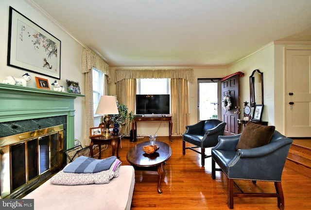 living room with crown molding, a premium fireplace, and wood finished floors