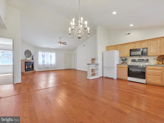 kitchen with a glass covered fireplace, light brown cabinets, white appliances, visible vents, and high vaulted ceiling
