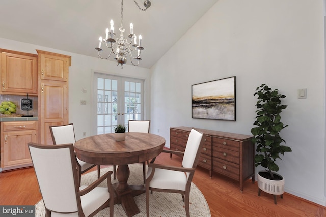 dining room with baseboards, an inviting chandelier, light wood-type flooring, french doors, and high vaulted ceiling