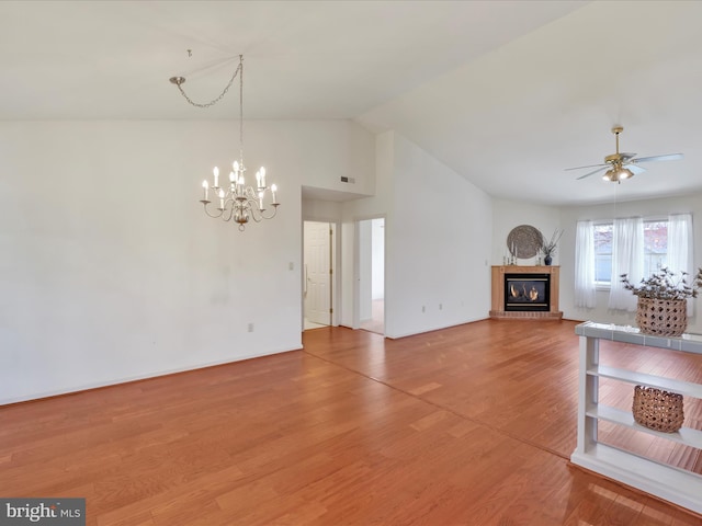 unfurnished living room featuring visible vents, a fireplace, light wood finished floors, ceiling fan with notable chandelier, and lofted ceiling