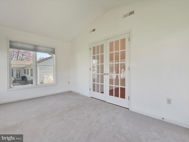 carpeted empty room with french doors, baseboards, visible vents, and lofted ceiling