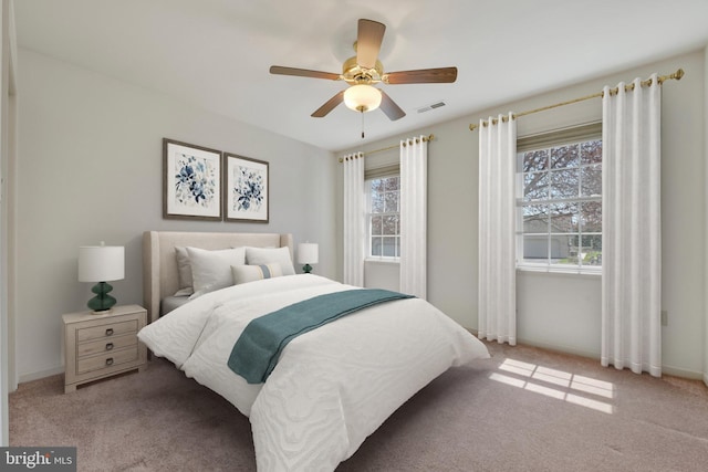 bedroom featuring visible vents, baseboards, ceiling fan, and light colored carpet