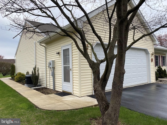 view of home's exterior featuring driveway, cooling unit, and a garage