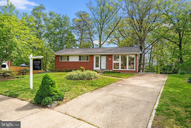 single story home with brick siding, driveway, and a front yard