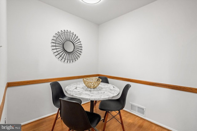 dining space with baseboards, visible vents, and wood finished floors