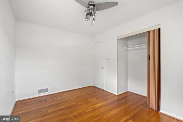 unfurnished bedroom featuring visible vents, a closet, wood finished floors, baseboards, and a ceiling fan
