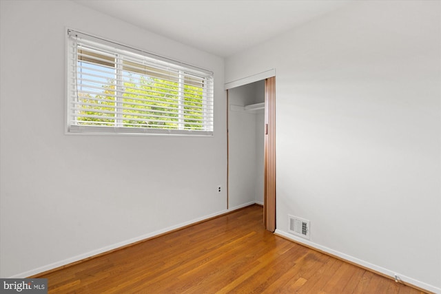 unfurnished bedroom featuring visible vents, baseboards, wood finished floors, and a closet