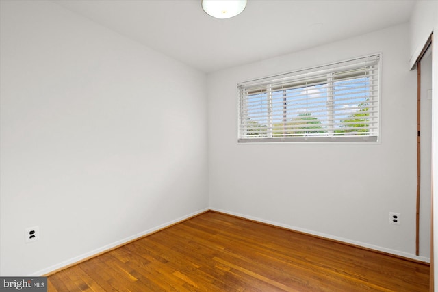 spare room featuring baseboards and wood finished floors