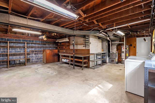 unfinished basement featuring washing machine and clothes dryer, concrete block wall, water heater, a workshop area, and heating unit