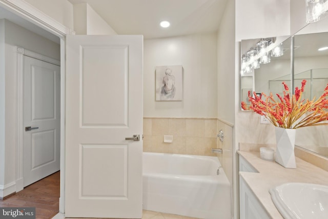 full bathroom featuring vanity, a bath, and wood finished floors