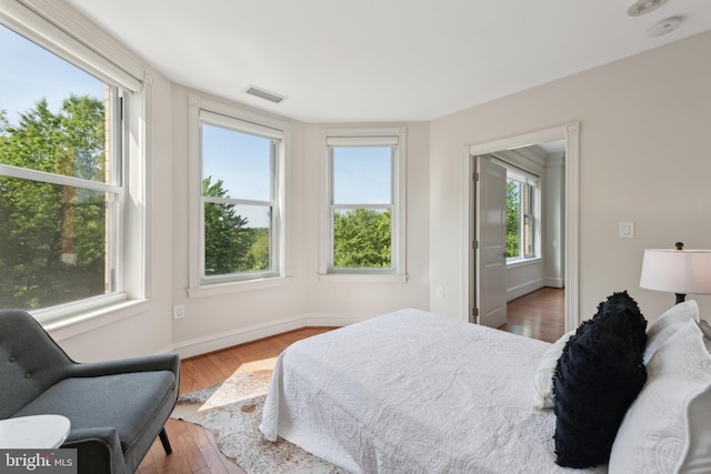 bedroom with visible vents, baseboards, and wood finished floors