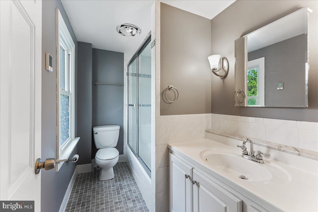bathroom featuring baseboards, toilet, tile walls, vanity, and tile patterned floors