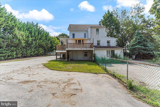 view of front of property featuring aphalt driveway, fence, a front lawn, a chimney, and a deck