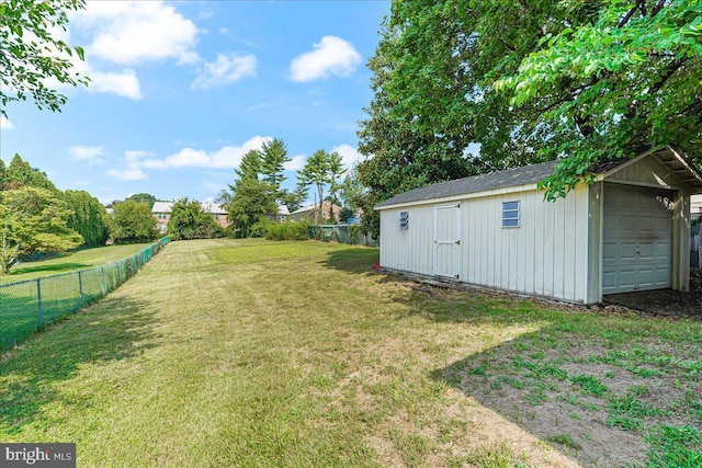 view of yard featuring a garage, a fenced backyard, and an outbuilding