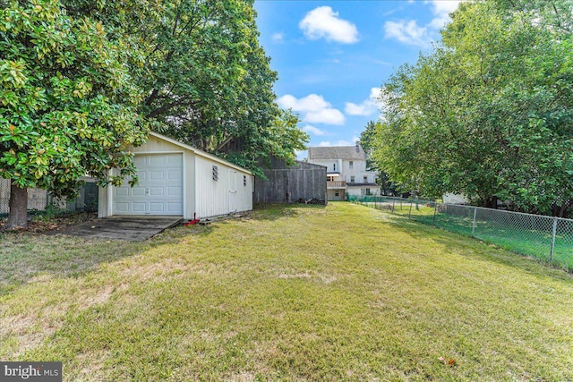 view of yard featuring a garage, a fenced backyard, and an outdoor structure