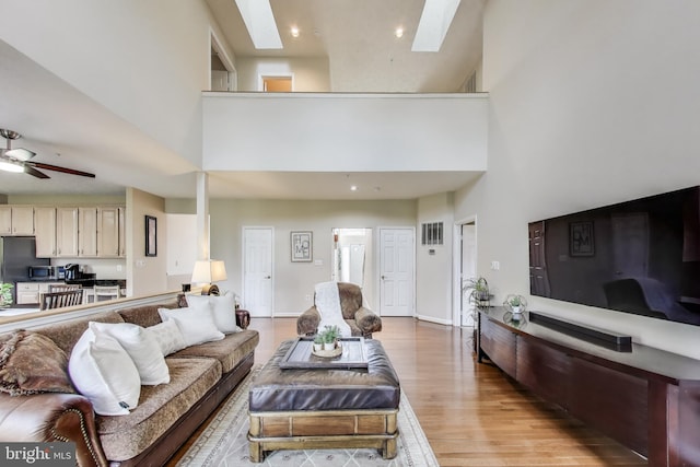 10107 Linford Ter, Lanham, MD 20706 - living room featuring a skylight, light wood-type flooring, ceiling fan, and a high ceiling