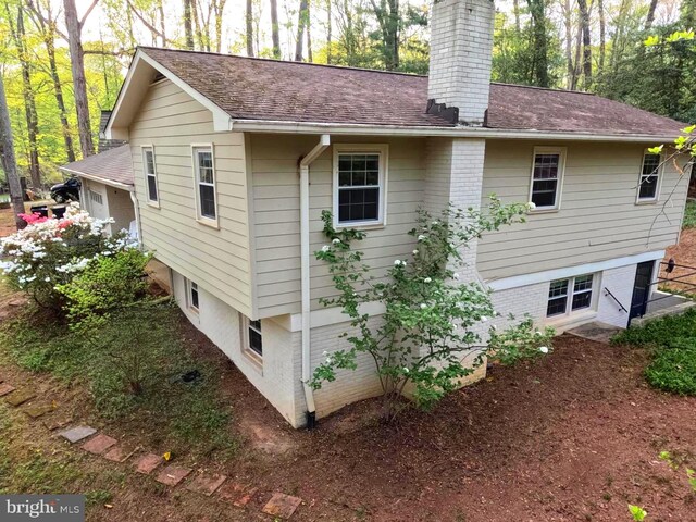 back of property featuring a chimney and a shingled roof