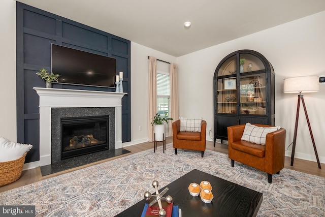 living room featuring baseboards, a fireplace with flush hearth, and wood finished floors