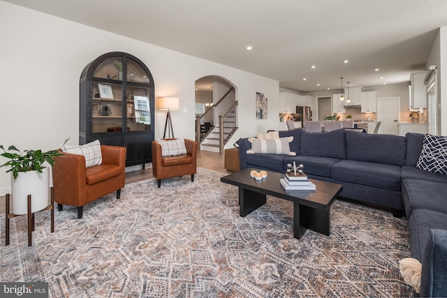 living area with stairs, arched walkways, recessed lighting, and wood finished floors