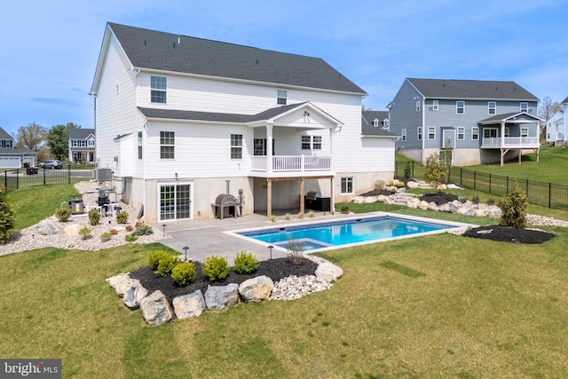 rear view of house with a lawn, a pool with connected hot tub, a fenced backyard, and a patio area