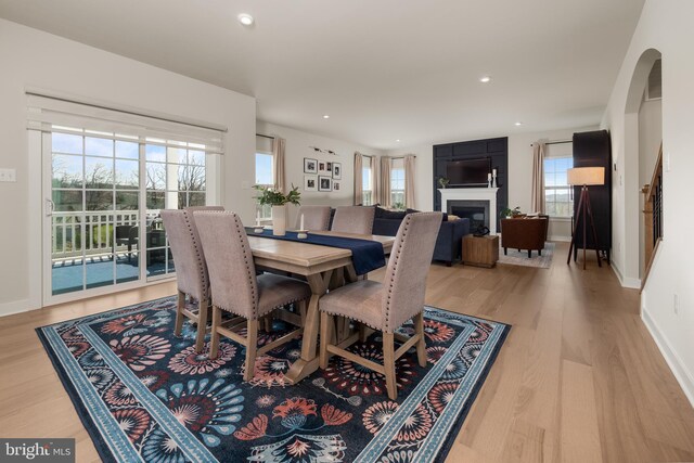 dining area with light wood-style floors, baseboards, a fireplace, and a healthy amount of sunlight