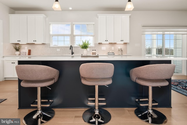 kitchen featuring light countertops, white cabinets, a kitchen island, and backsplash
