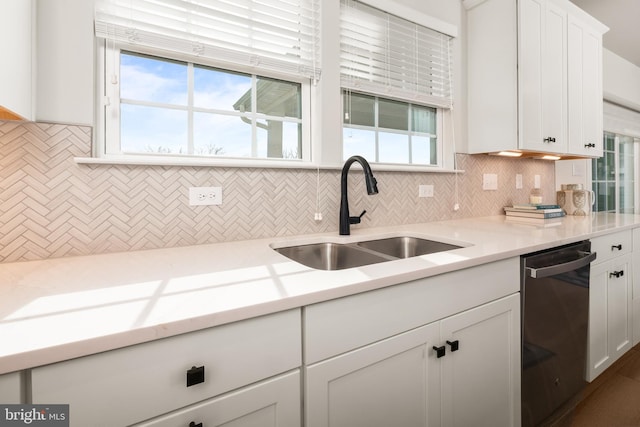 kitchen featuring decorative backsplash, stainless steel dishwasher, a sink, light countertops, and white cabinets