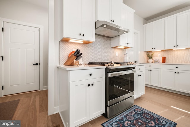 kitchen with gas range, light countertops, white cabinets, light wood-style floors, and under cabinet range hood