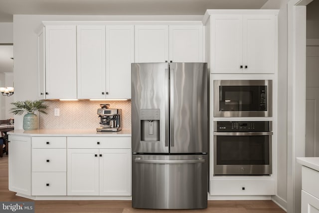 kitchen featuring light countertops, stainless steel appliances, white cabinetry, and decorative backsplash