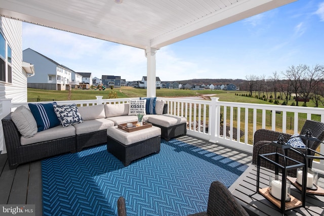 wooden terrace featuring a residential view, a lawn, and an outdoor living space