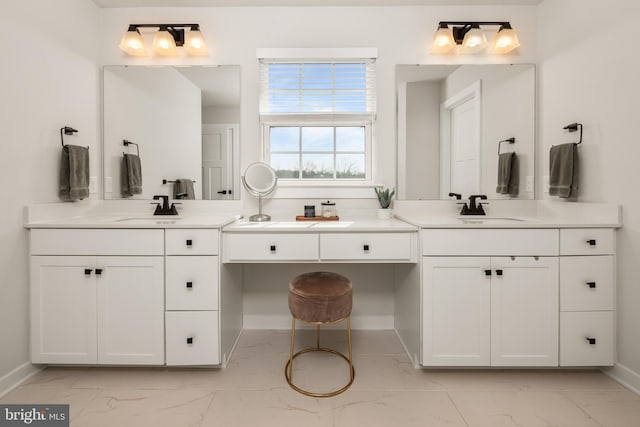 full bath featuring baseboards, a sink, marble finish floor, and two vanities