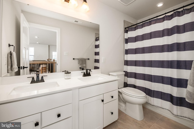 bathroom featuring double vanity, toilet, visible vents, and a sink