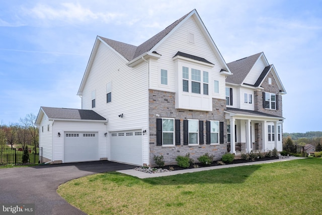 craftsman-style home with a garage, aphalt driveway, fence, a front yard, and stone siding